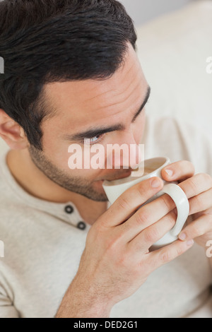 Nachdenklich gut aussehender Mann, Kaffee zu trinken, während Sie gemütlich auf dem sofa Stockfoto