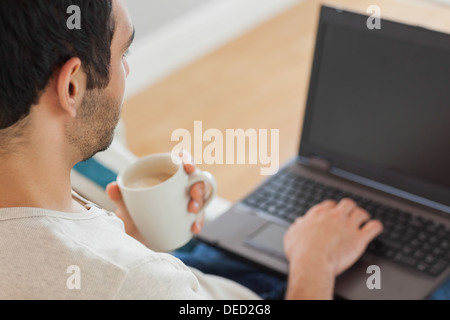 Gut aussehender Mann, Kaffee zu trinken, während mit seinem laptop Stockfoto