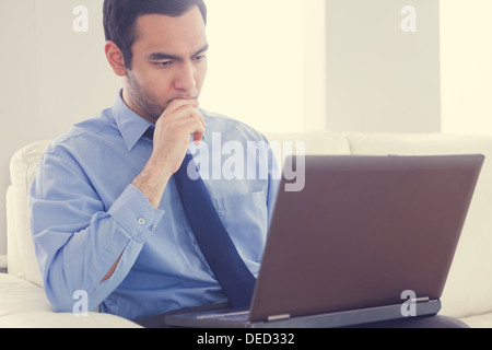 Mann mit einem Laptop auf einem Sofa sitzt betont Stockfoto