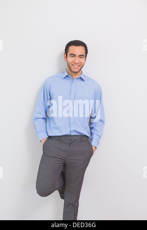 Erfreut Mann an eine Wand gelehnt, Hände in den Taschen Stockfoto
