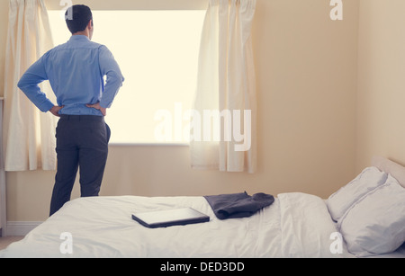 Rückansicht eines Mannes vor einem Fenster stehen und blickte heraus, dass es Stockfoto