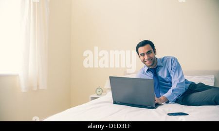 Content-Mann liegt im Bett mit einem laptop Stockfoto