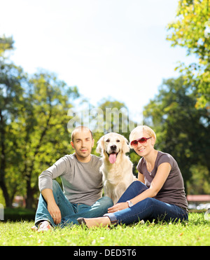 Lächelnd junges Paar umarmt einen Labrador Retriever Hund in einem park Stockfoto