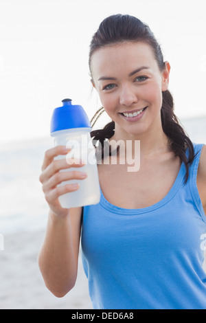 Lächelnde Frau zeigt ihre Wasserflasche Stockfoto