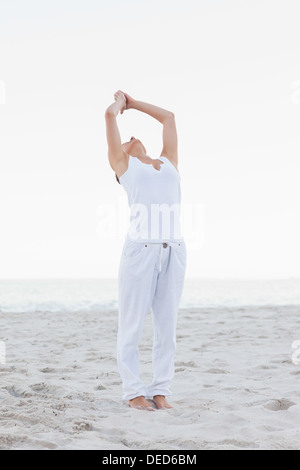 Aktive Frau praktizieren Yoga am Strand Stockfoto