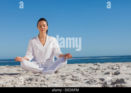 Frau in weiß beim Yoga am Strand Stockfoto