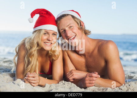 Paar am Strand tragen Weihnachtsmützen liegen Stockfoto