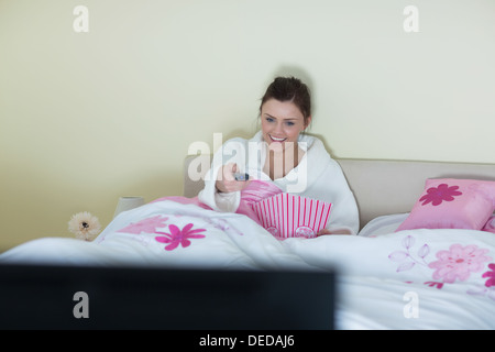 Brünette tragen Bademantel vor dem Fernseher lachen Stockfoto