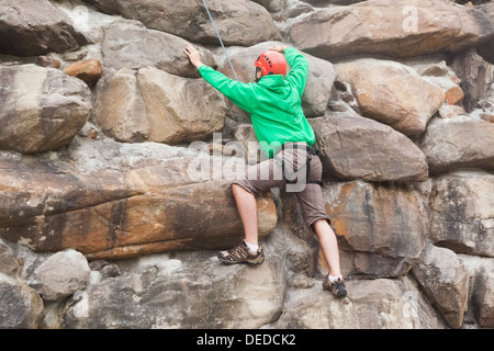 Entschlossenen Mann Skalierung einer riesigen Felswand Stockfoto