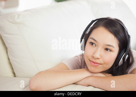 Hübsche Asiatin auf dem Sofa liegen und Musik hören Stockfoto