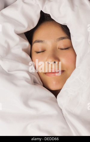 Junge asiatische Frau eingehüllt in ihre Bettdecke Stockfoto