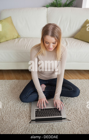 Blonde Frau sitzt am Boden mit laptop Stockfoto
