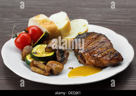 Schweineschnitzel mit Sauce, Senf und gegrilltes Gemüse auf dem Teller Stockfoto