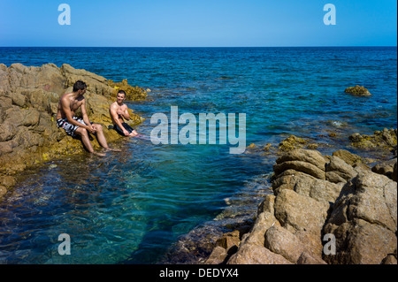 Capo Comino, Italien, Badegäste auf der felsigen Küste Capo Comino in Sardinien Stockfoto