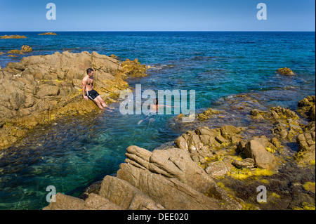 Capo Comino, Italien, Badegäste auf der felsigen Küste Capo Comino in Sardinien Stockfoto