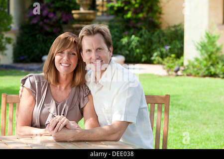 Glücklich Mitte im Alter von Mann und Frau verheiratetes Paar in den Dreißigern, zusammen draußen in einem Garten sitzen an einem Tisch sitzen Stockfoto