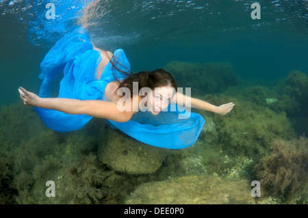 Eine junge Frau mit langen Haaren in blauem Kleid Tauchgänge Unterwasser im Schwarzen Meer Stockfoto