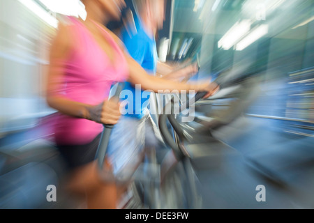 Bewegungsunschärfe Zoom Foto von einem interracial Gruppe von Mann und Frau, die auf Geräte in einem Fitnessstudio Stockfoto