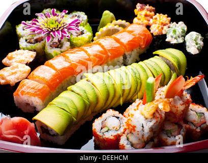 Verschiedene Sushi-Rollen auf einer schwarzen Platte. Stockfoto