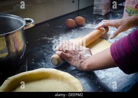 Frau Rollen Blätterteig für die Herstellung von Apfelkuchen in einer Küche Stockfoto