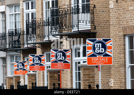 Immobilienmakler für Verkauf und verkauft Anzeichen auf eine Reihe von modernen terrassenförmig angelegten Apartments. Stockfoto