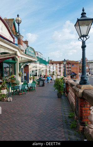 Menschen Essen außerhalb Cafés und Restaurants entlang der West Cliff Arcade mit Blick auf den Hafen von Ramsgate. Stockfoto