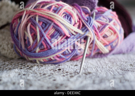 Bunte Wollknäuel mit Stricknadeln auf einer Spitze-Oberfläche Stockfoto