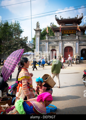 Flower Hmong Leute am Sonntagsmarkt in Bac Ha, Vietnam.  Die Bac Ha Tempel erhebt sich im Hintergrund. Stockfoto