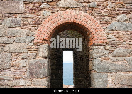 Blick durch Stein und Ziegel, gewölbte Öffnung in das alte Wheal Coates Tin Mine Maschinenhaus in der Nähe von St. Agnes, Cornwall, England. Stockfoto