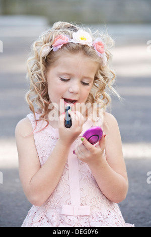 Ziemlich sieben Jahre altes Mädchen tragen rosa und Auftragen von Lippenstift Stockfoto