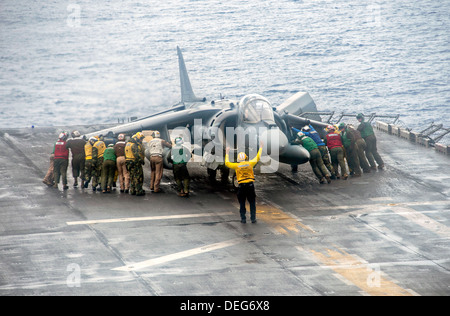 US Matrosen und Marinesoldaten bewegen ein Marinekorps AV-8 b Harrier II Flugzeug während ein Sturm auf dem Flugdeck der amphibischen Angriff Schiff USS Boxer 11. September 2013 im Gange im Pazifischen Ozean 11. September 2013. Die Boxer war im Gange, in den USA 7. Flotte Aufgabengebiet maritimer Sicherheitsoperationen und Theater Sicherheitsbemühungen Zusammenarbeit zu unterstützen. Stockfoto