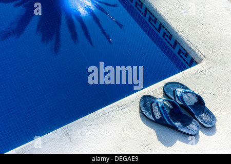 Pool - ein paar Flip Flop Schuhe neben einem Schwimmbad. Stockfoto