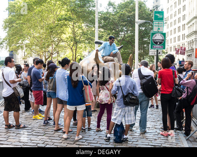 Touristen im Laden Stier Skulptur in Bowling Green Park, New York Stockfoto