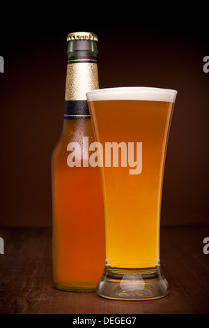 Ein Glas und eine Flasche Bier auf einem Holztisch. Stockfoto