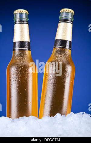 Zwei Bierflaschen sitzen auf Eis über einen blauen Hintergrund. Stockfoto