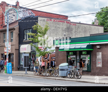 Menschen mit Geldautomaten von Canada Trust Bank mit "Angst ist dein Leben ruinieren" Graffiti auf angrenzende Wand in Queen Street West, Toronto Stockfoto