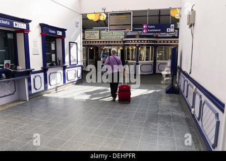 Eine Frau, ein Spaziergang durch das Foyer des Bahnhofs in King's Lynn, Norfolk. Stockfoto