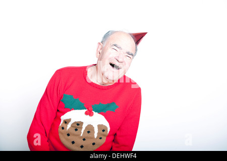 Senior erwachsenen Mann trägt einen Weihnachtspullover ein roter Partyhut Stockfoto