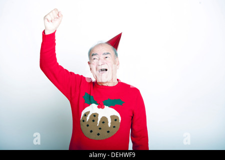 Älteren Erwachsenen Mannes tragen Weihnachtspullover seinen Arm in die Luft heben Stockfoto