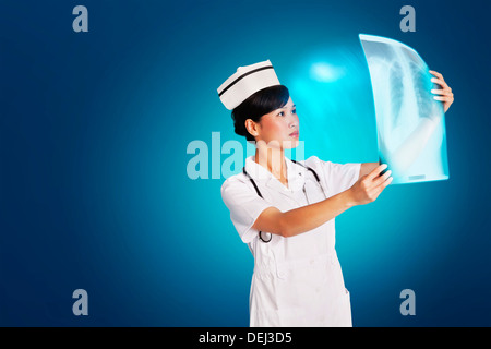 Ärztin, die Analyse der Röntgen-Bericht in blauem Hintergrund Stockfoto