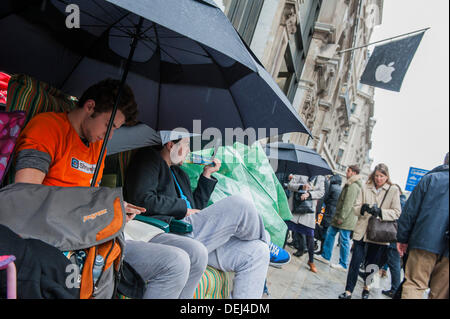 London, UK. 19. September 2013. Die Warteschlange für den Launch des Apple i-Phone 5 kauert unter Sonnenschirmen im Regen. Bildnachweis: Guy Bell/Alamy Live-Nachrichten Stockfoto