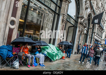 London, UK. 19. September 2013. Die Warteschlange für den Launch des Apple i-Phone 5 kauert unter Sonnenschirmen im Regen. Bildnachweis: Guy Bell/Alamy Live-Nachrichten Stockfoto