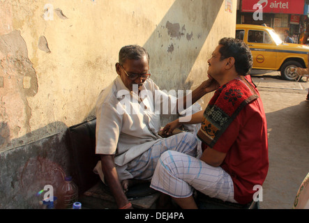 Straße Barbier rasieren einen Mann mit einer offenen Rasierklinge auf einer Straße in Kolkata, Westbengalen, Indien am 24. November 2012 Stockfoto