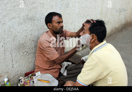 Straße Barbier rasieren einen Mann mit einer offenen Rasierklinge auf einer Straße in Kolkata, Westbengalen, Indien am 25. November 2012 Stockfoto