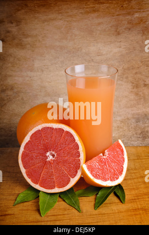 Glas frischer Druckfarbe Grapefruitsaft und Grapefruits auf einem hölzernen Hintergrund Stockfoto