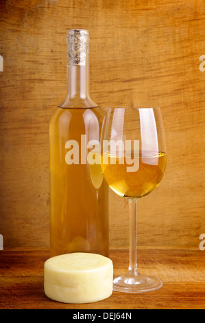 Glas und Flasche Weißwein mit Käse auf einem hölzernen Vintage-Hintergrund Stockfoto
