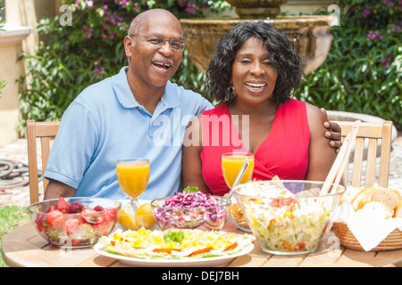 Glücklich, Lächeln, Mann und Frau senior afrikanischen amerikanischen Ehepaar, die gesunde Ernährung an einem Picknicktisch außerhalb Stockfoto