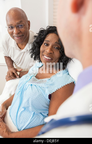 Glücklich senior afroamerikanische Frau Patient erholt sich im Krankenhaus mit männlichen Arzt und Ehemann Stockfoto