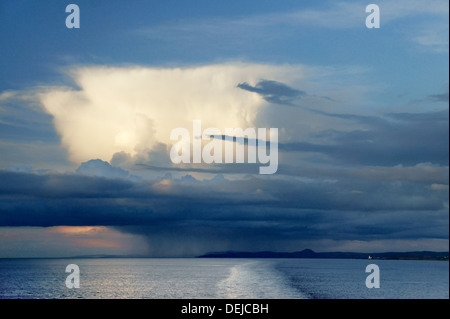 Amboss Top Cumulonimbus Regenwolke erhebt sich über Stratocumulus und eine Regendusche über Corsewall Lighthouse, Loch Ryan, irische See, UK Stockfoto