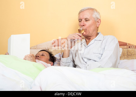 Älteres Paar im Bett Glas Alkohol und Buch Stockfoto